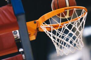 Basketball scoring basket at a sports arena. Scoring the winning points at a basketball game. The orange basketball ball flies through the basket