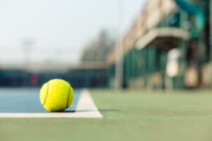 High-angle close-up of a fluorescent yellow tennis ball in the court